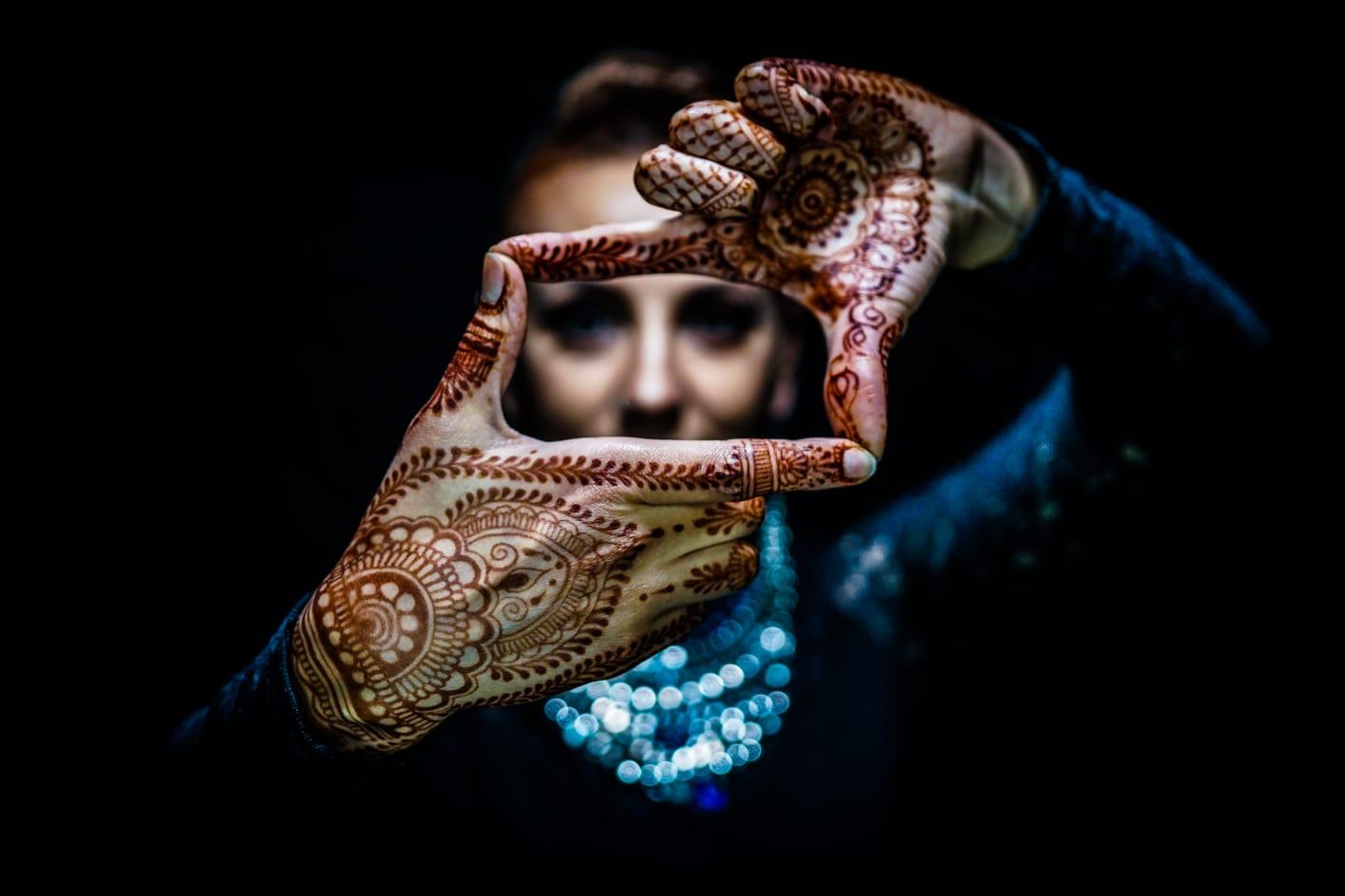Mit Henna verzierte Hände vor dunklem Hintergrund