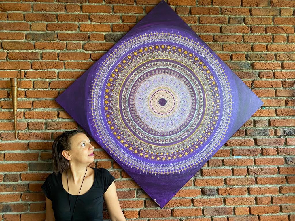 Frau neben einem großformatigen violetten Mandala